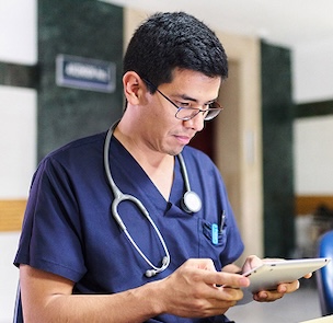 Doctor in blue scrubs using a tablet in a hospital setting