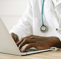 Doctor typing on a laptop with a stethoscope around their neck