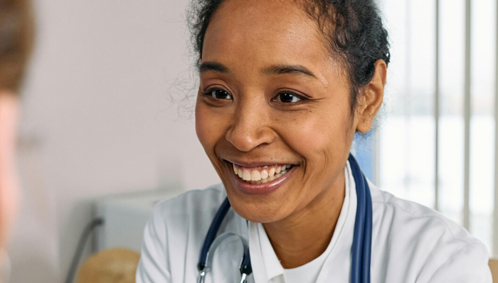 Smiling doctor with stethoscope meeting patient in office