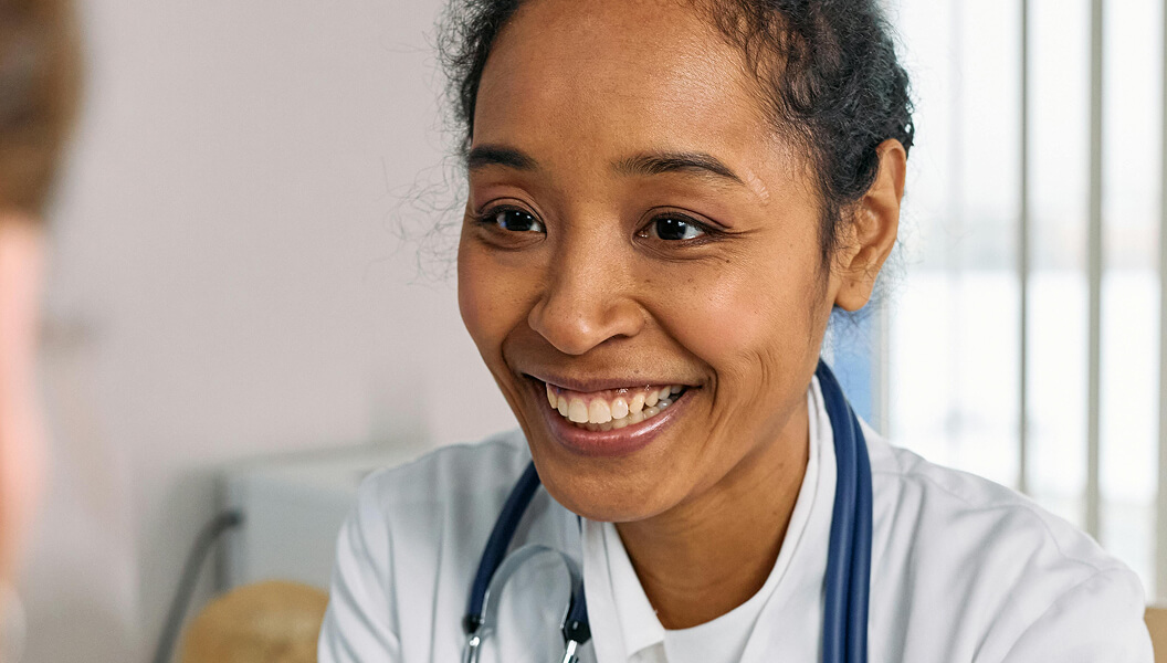Smiling doctor with stethoscope meeting patient in office