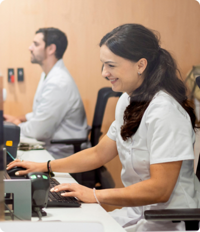 Two smiling healthcare professionals working at a computer station in a medical office