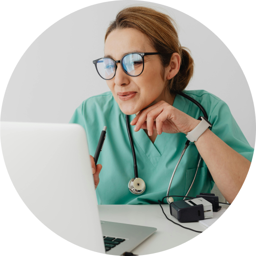 Doctor in scrubs using laptop for telehealth consultation in office setting