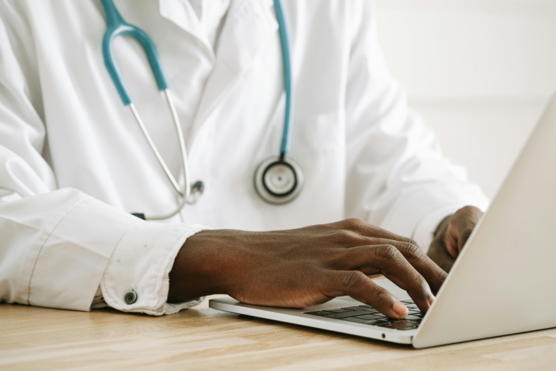 Doctor typing on a laptop while wearing a stethoscope