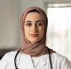 Female doctor in a hijab with a stethoscope looking confidently at the camera in a bright room