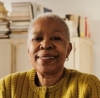 Smiling person in cozy room with books and shelves in the background