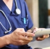 Doctor in blue scrubs using a digital tablet in a medical setting.