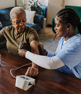 Nurse checking blood pressure of elderly woman at home