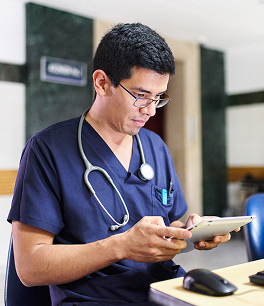 Doctor in blue scrubs using a tablet in a hospital setting