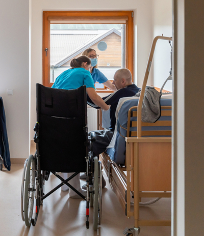 Healthcare professionals assisting a patient in a wheelchair in a bright medical facility room