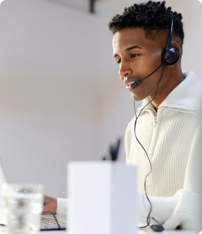 Customer service representative working on a laptop with a headset in a modern office environment