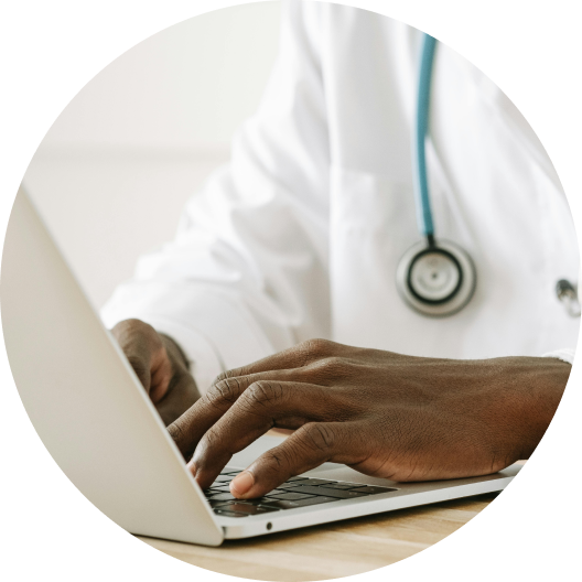 Doctor typing on a laptop wearing a stethoscope in a clinic office