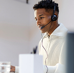 Man with headset working at a computer desk in an office setting