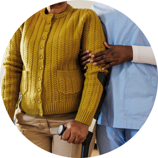 Healthcare worker assisting person with crutch in yellow sweater