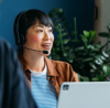 Person wearing a headset working on a laptop in an office environment