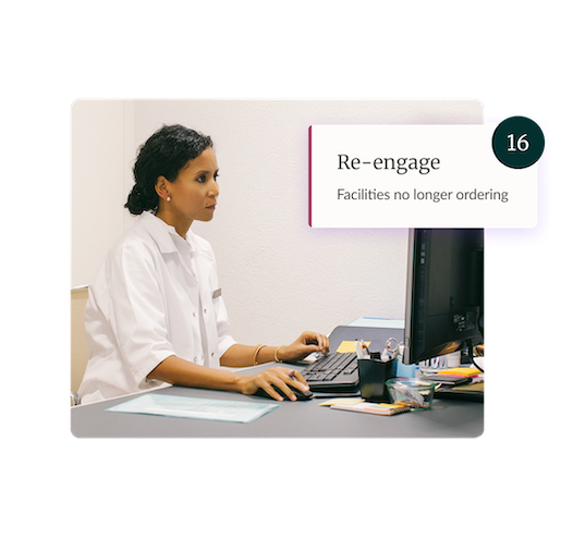 Woman in a white coat working at a computer in an office setting.